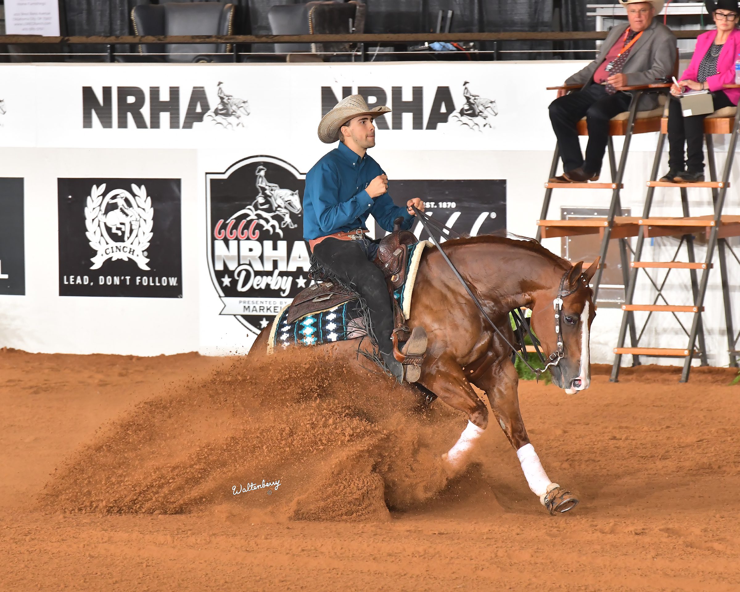 A male rider and horse sliding in an arena