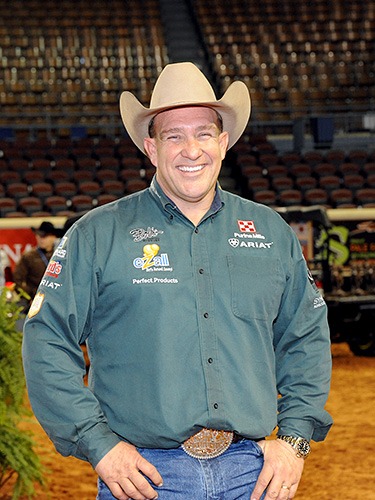 Man in a green shirt with a cowboy hat, smiling at an event